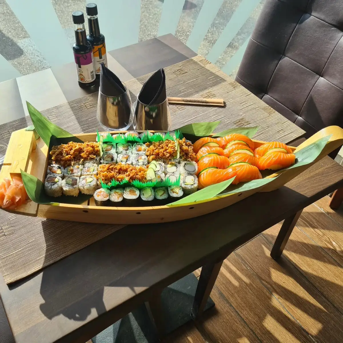 Plateau bateau garni de makis, californias et sushis saumon, servi en salle chez Sushi House